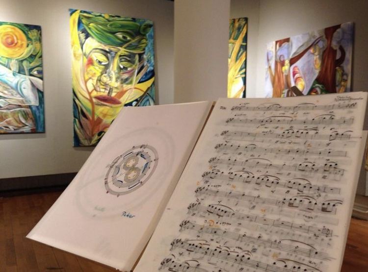 Circular and linear scores displayed on a stand in a gallery, with large colourful paintings on the walls behind
