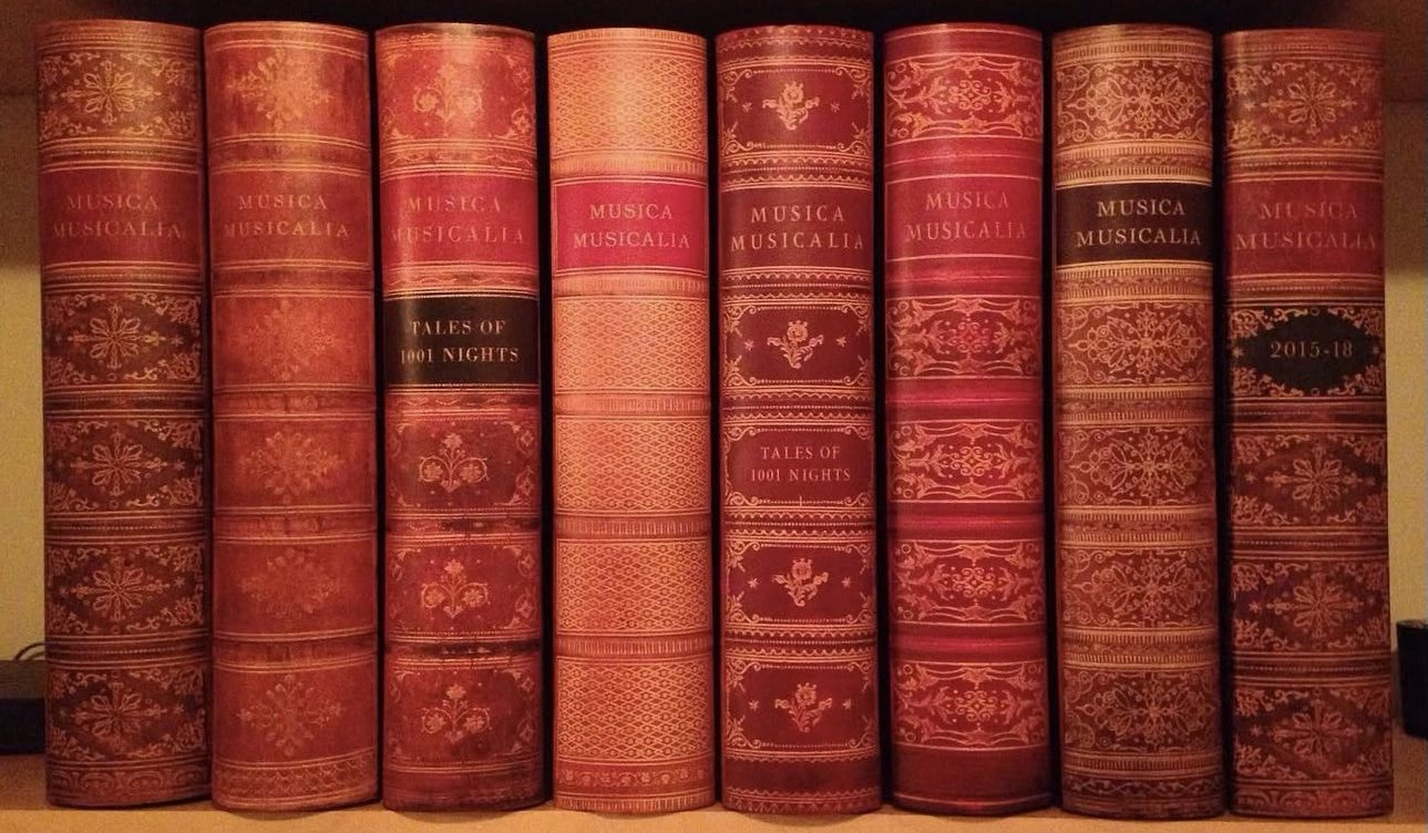 Eight tall volumes bound in red and gold-tooled covers, each spine titled Musica Musicalia, two also labelled Tales of 1001 Nights and one labelled 2015–18