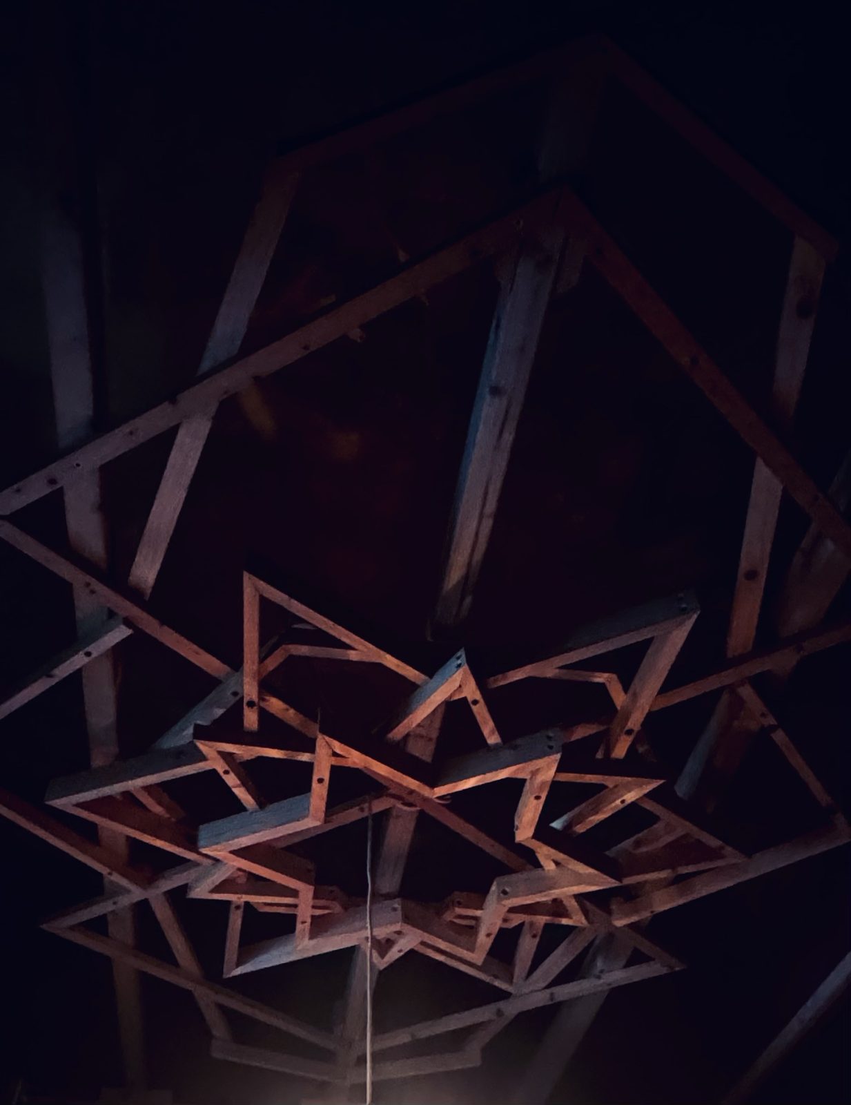 The wooden star structure at night, lit warm red against the dark ceiling
